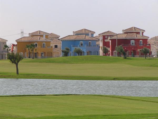 Ferienhäuser am Golfplatz
Unmittelbar am Golfplatz sind die Reihen der Häuser. Hier sieht man hinter dem Wasserhindernis am Golfplatz sind 3 Villen vom Typ Perdiguera zu sehen.