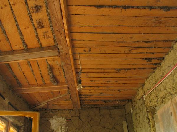Zimmer im Rohbau
Die Wände sind noch unverputzter Lehm mit Stroh. Die Decke besteht aus Holz. Zwischen den Brettern sind schmale Spalten, durch welche darüberliegender Lehm und Stroh quillt.